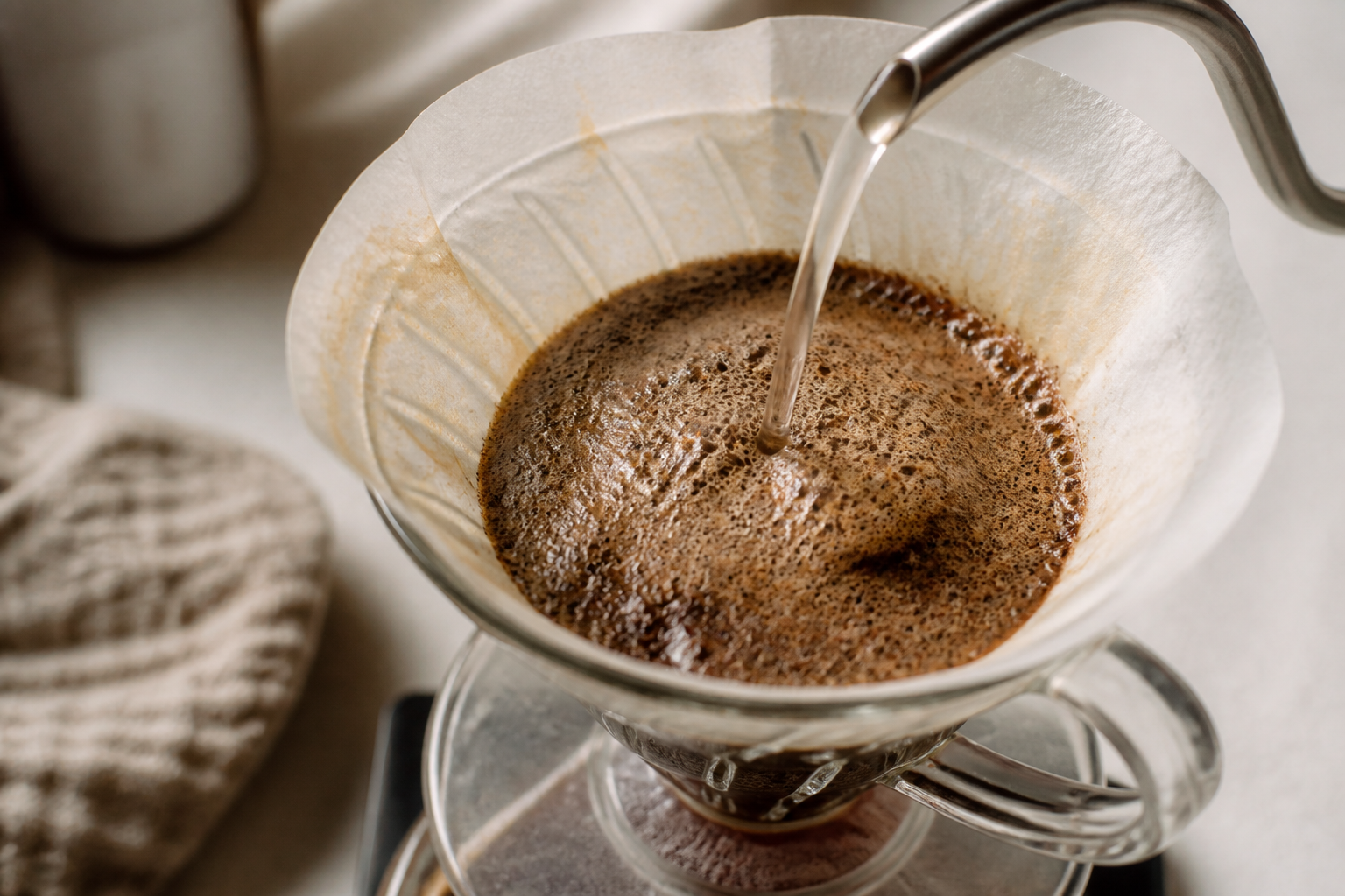 Coffee grounds blooming and releasing bubbles as hot water is poured over them in a pour-over dripper